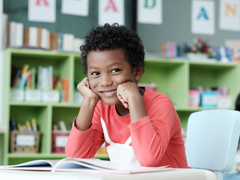 Young boy sitting at desk with book in school