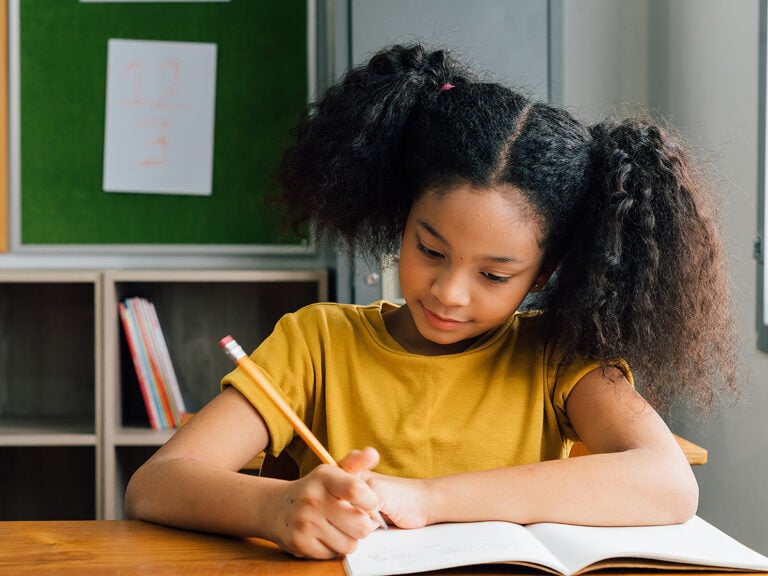 Young smling girl taking notes at school