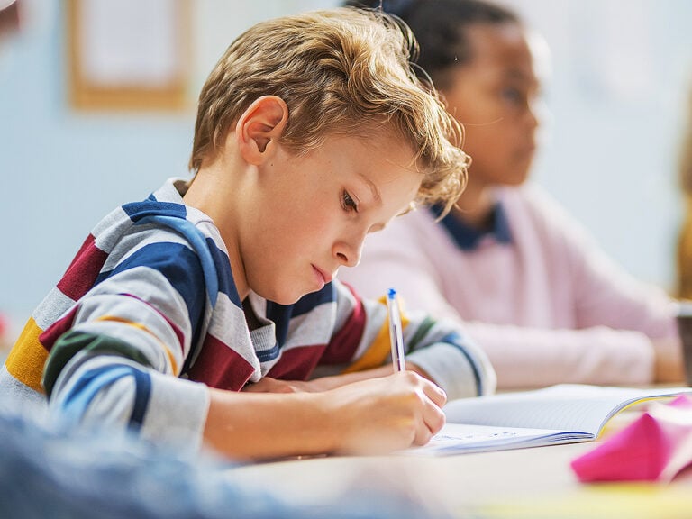 Middle school student writing in notebook at school