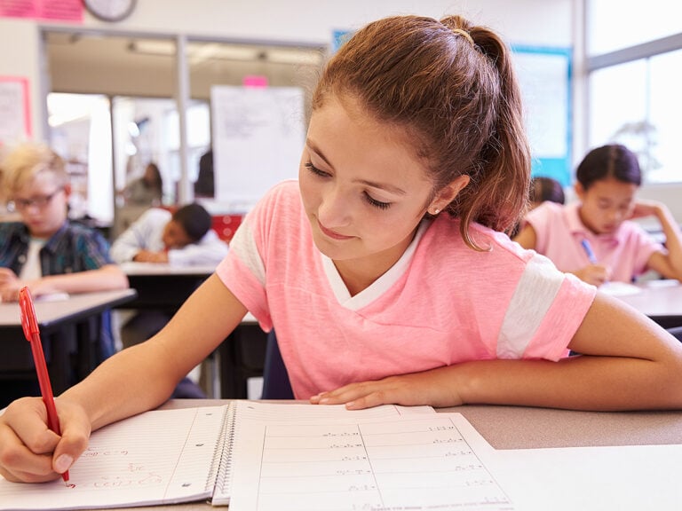 Young girl writing at her desk in class