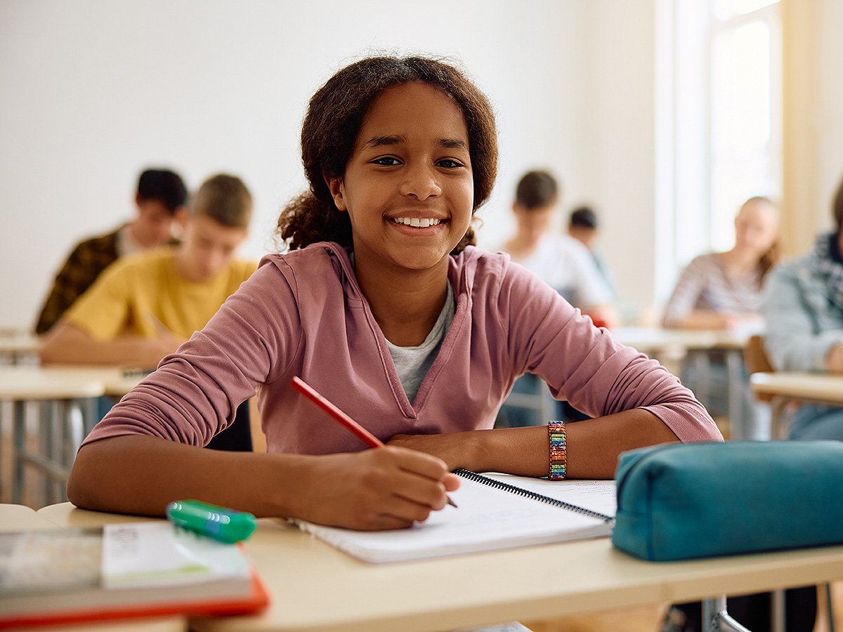 Smiling teenage girl taking notes in class