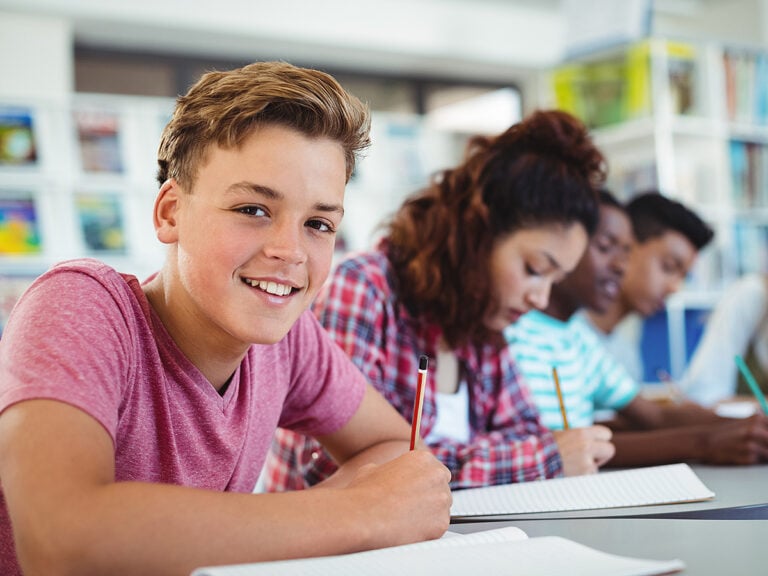 Portrait of happy school boy studying in library