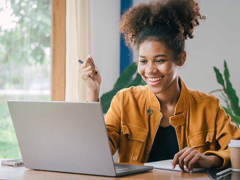 High school girl smiling doing homework on laptop