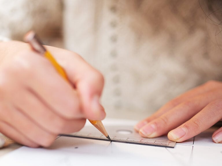 child doing math homework, using a ruler to measure shape