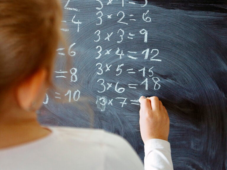 Girl doing multiplication problems on blackboard